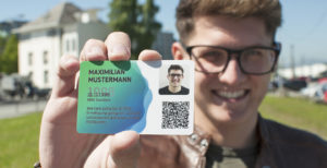 Junger Mann streckt neue aha card in die Kamera