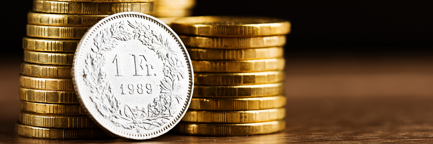 one swiss frank coin and gold money on the desk